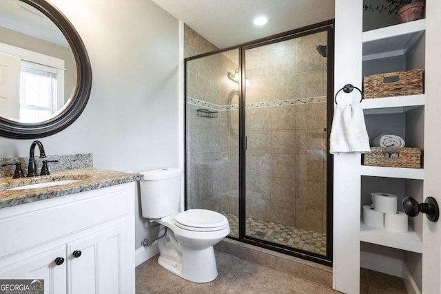 bathroom featuring a shower with door, vanity, tile patterned flooring, and toilet