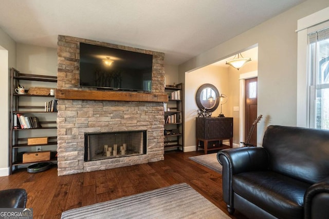 living room featuring a stone fireplace and dark hardwood / wood-style floors