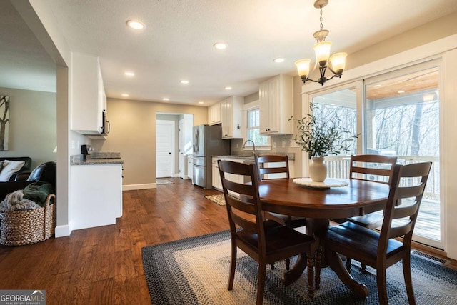 dining room with dark wood-type flooring, sink, and a chandelier