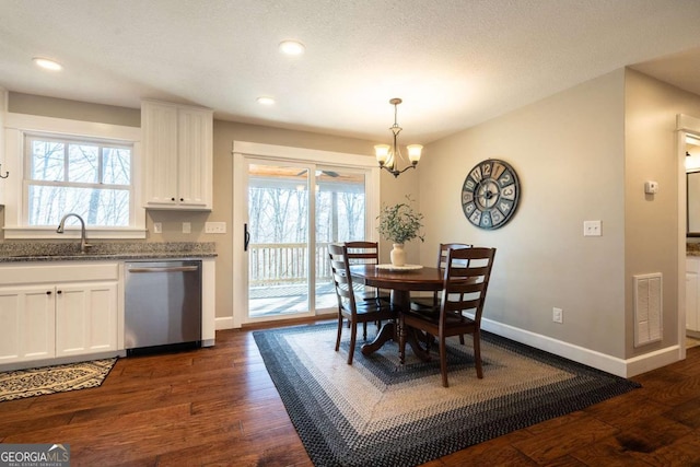 dining room with plenty of natural light, sink, dark wood-type flooring, and an inviting chandelier