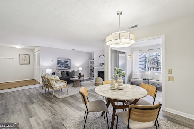 dining space featuring a textured ceiling, a fireplace, and light wood-type flooring