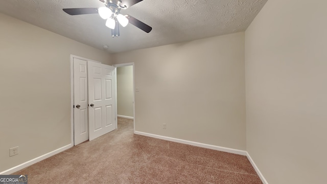 carpeted spare room featuring ceiling fan and a textured ceiling