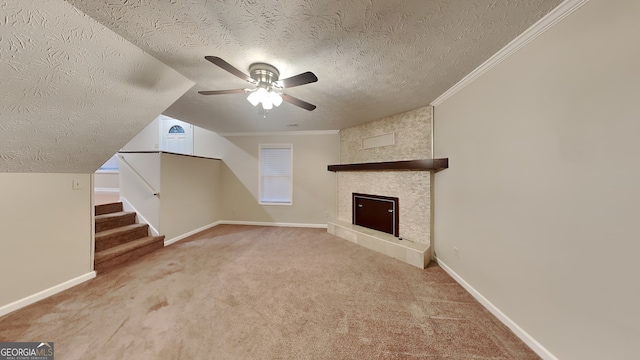 unfurnished living room featuring a textured ceiling, ornamental molding, carpet floors, ceiling fan, and a fireplace