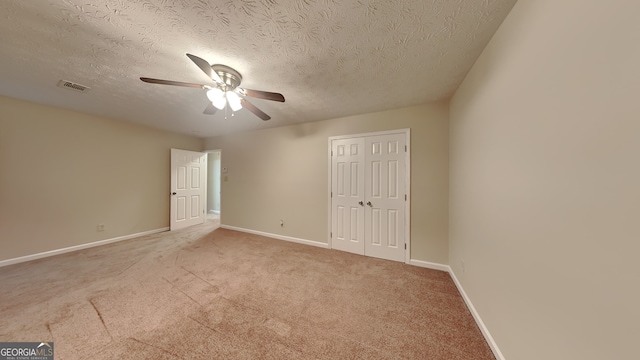 spare room featuring light carpet, a textured ceiling, and ceiling fan