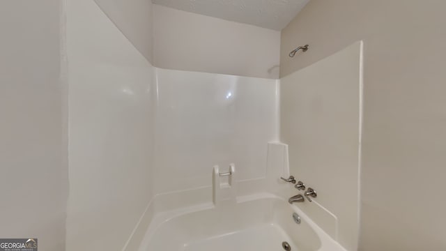 bathroom with  shower combination and a textured ceiling