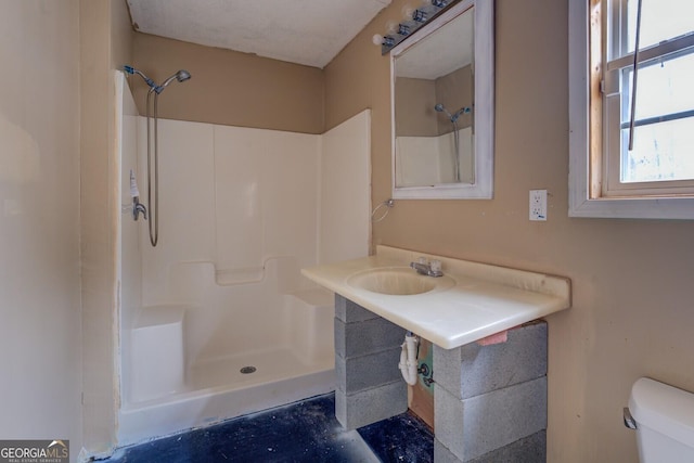 bathroom featuring sink, a shower, and toilet