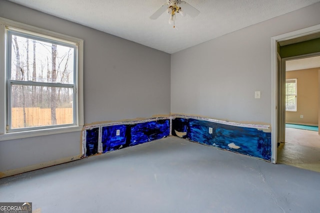 empty room with concrete flooring, a wealth of natural light, and ceiling fan