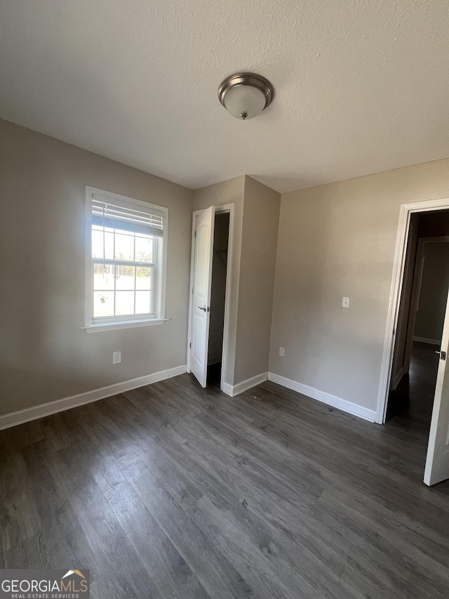 unfurnished bedroom featuring dark wood-type flooring and a textured ceiling