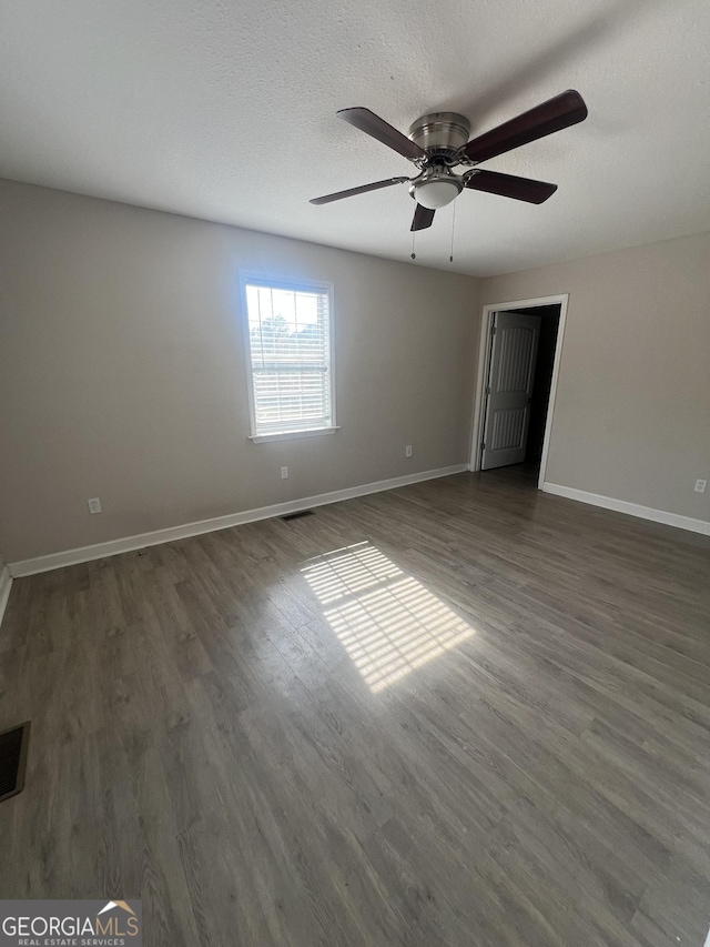 unfurnished room featuring ceiling fan, dark hardwood / wood-style floors, and a textured ceiling