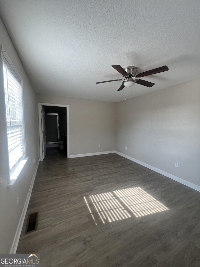 unfurnished room with ceiling fan, dark hardwood / wood-style floors, and a textured ceiling