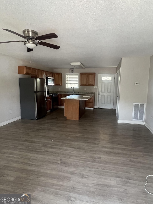 kitchen featuring dark hardwood / wood-style floors, stainless steel appliances, a center island, and a textured ceiling