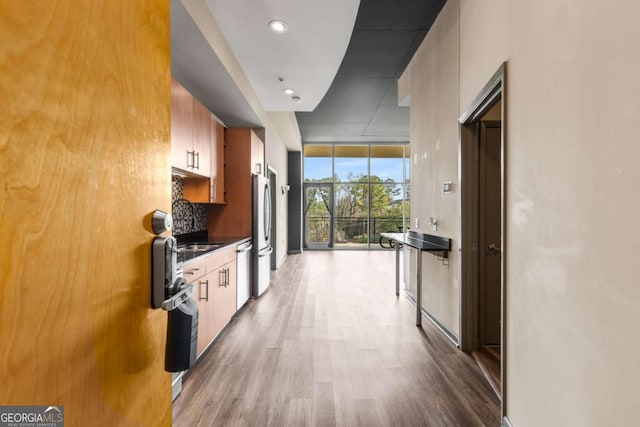 kitchen with expansive windows, tasteful backsplash, appliances with stainless steel finishes, and light wood-type flooring