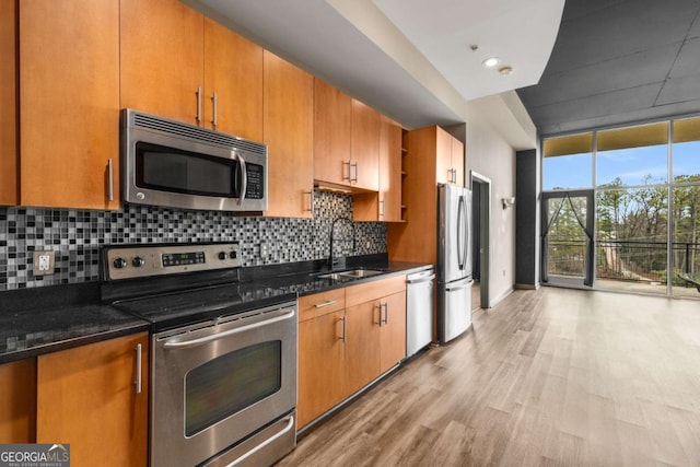 kitchen with expansive windows, stainless steel appliances, sink, and dark stone countertops