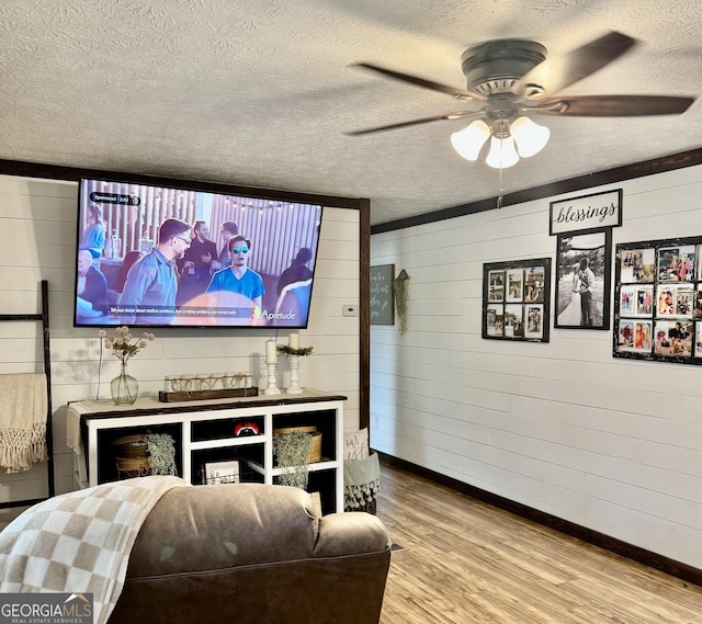 living room featuring ceiling fan, wood-type flooring, and a textured ceiling