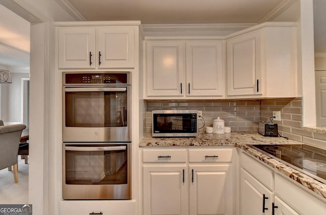 kitchen featuring backsplash, appliances with stainless steel finishes, and white cabinets