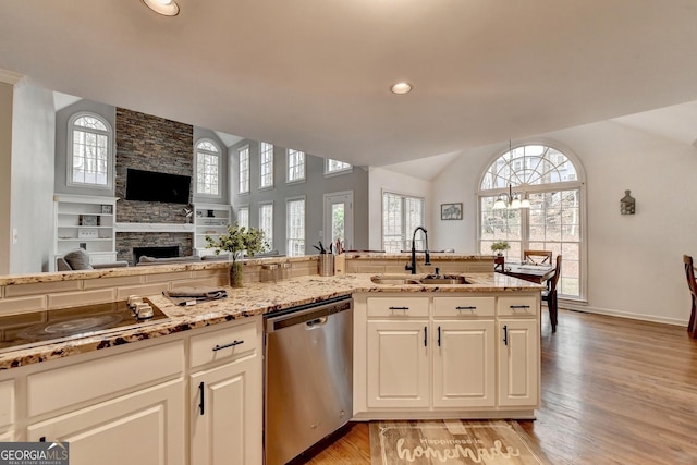 kitchen featuring a stone fireplace, sink, vaulted ceiling, stainless steel dishwasher, and black electric stovetop