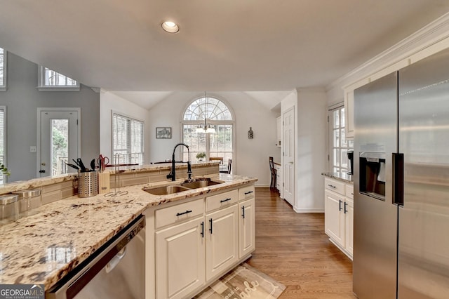 kitchen featuring vaulted ceiling, appliances with stainless steel finishes, sink, white cabinets, and light hardwood / wood-style flooring