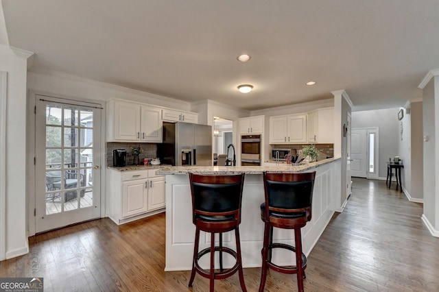 kitchen with white cabinetry, dark hardwood / wood-style flooring, decorative backsplash, stainless steel appliances, and crown molding