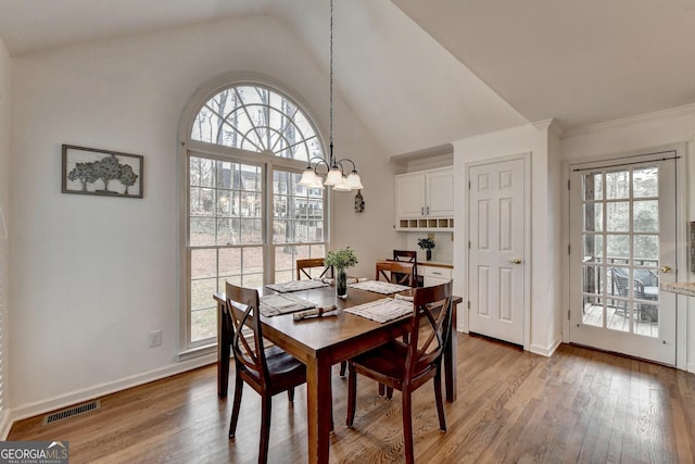 dining space with a wealth of natural light, light hardwood / wood-style flooring, and a chandelier