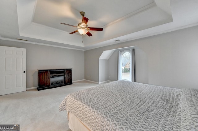 carpeted bedroom featuring a tray ceiling, ornamental molding, and ceiling fan