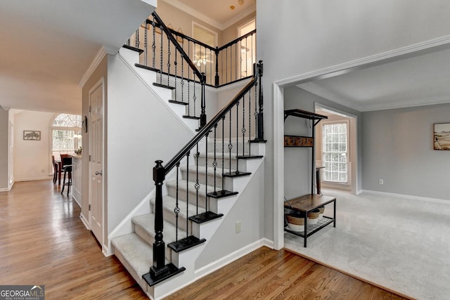 staircase featuring hardwood / wood-style flooring, ornamental molding, and a high ceiling