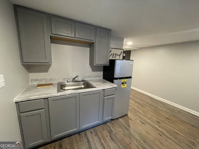 kitchen with stainless steel refrigerator, dark wood-type flooring, sink, and gray cabinetry