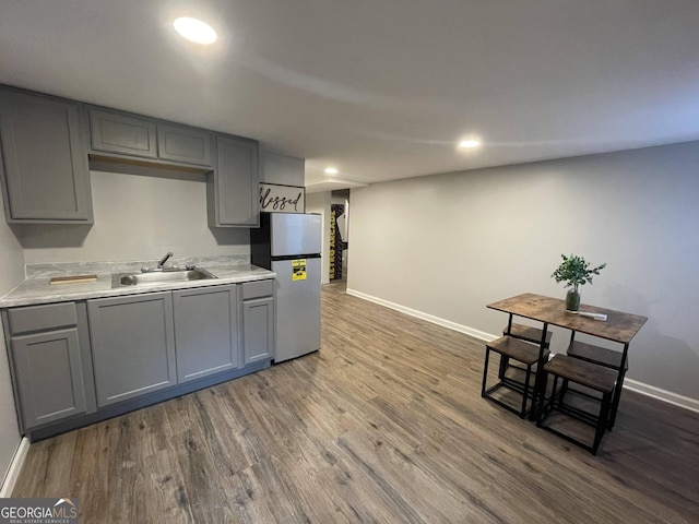 kitchen with stainless steel refrigerator, dark hardwood / wood-style flooring, sink, and gray cabinetry