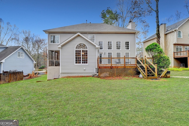 rear view of house with a wooden deck, a sunroom, and a lawn