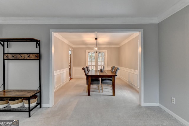 carpeted dining room featuring ornamental molding and a chandelier