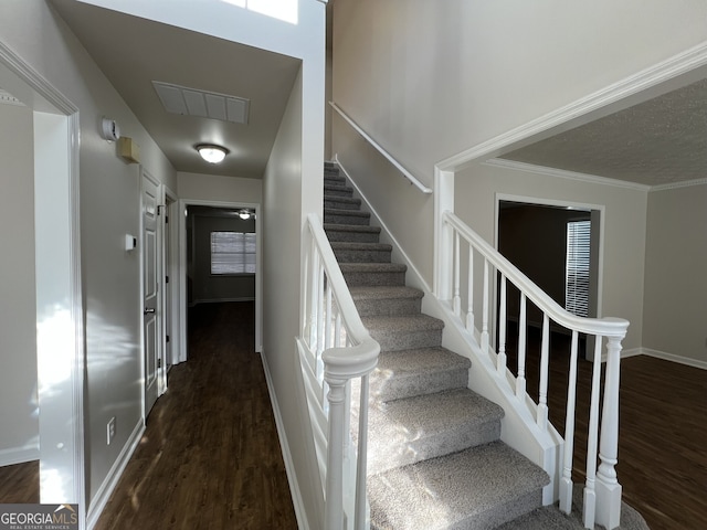 stairs with crown molding and wood-type flooring