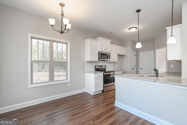 kitchen featuring appliances with stainless steel finishes, light stone counters, decorative light fixtures, sink, and white cabinetry