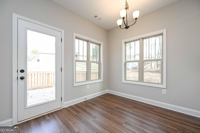 doorway to outside featuring dark hardwood / wood-style flooring and an inviting chandelier