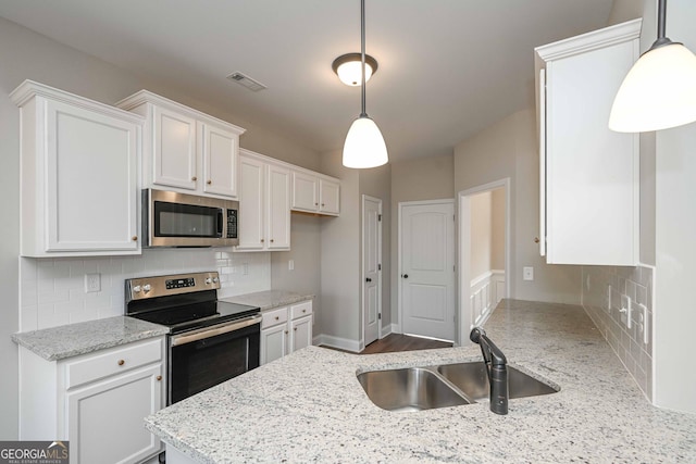 kitchen featuring hanging light fixtures, white cabinetry, stainless steel appliances, and sink