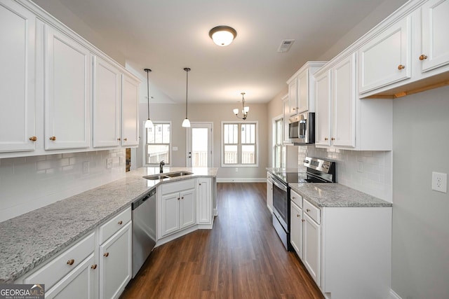 kitchen with white cabinetry, stainless steel appliances, light stone countertops, sink, and pendant lighting