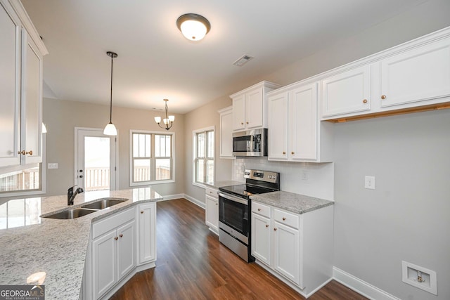 kitchen with stainless steel appliances, light stone counters, pendant lighting, sink, and white cabinetry