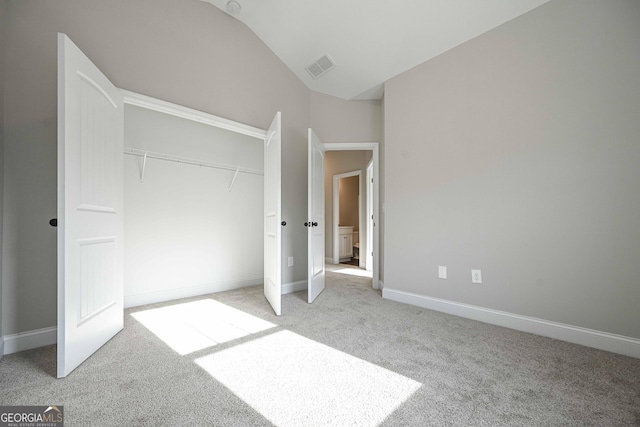 unfurnished bedroom featuring light carpet, a closet, and lofted ceiling