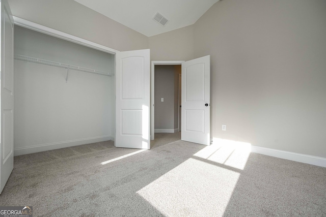 unfurnished bedroom featuring light carpet, a closet, and lofted ceiling