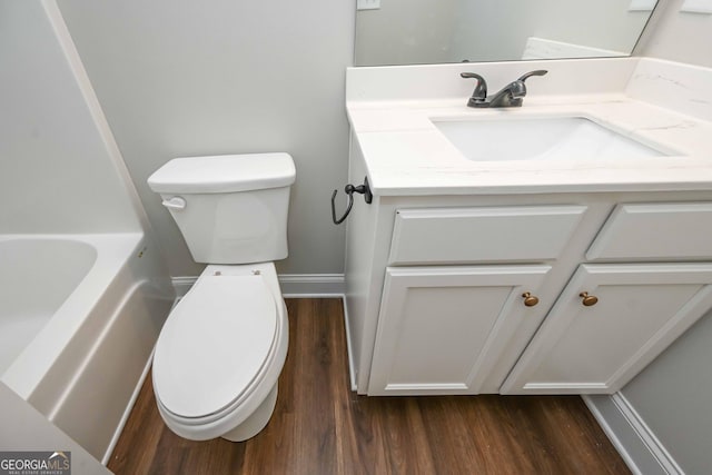 bathroom featuring hardwood / wood-style floors, toilet, a bathtub, and vanity