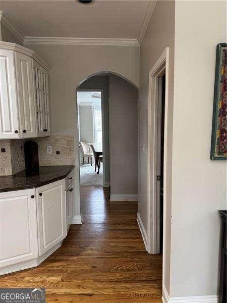 kitchen with dark hardwood / wood-style flooring, decorative backsplash, ornamental molding, and white cabinets