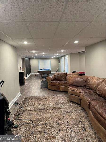 living room featuring hardwood / wood-style flooring, pool table, and a drop ceiling