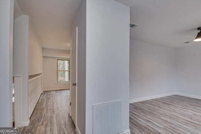 hall with light hardwood / wood-style flooring and a textured ceiling