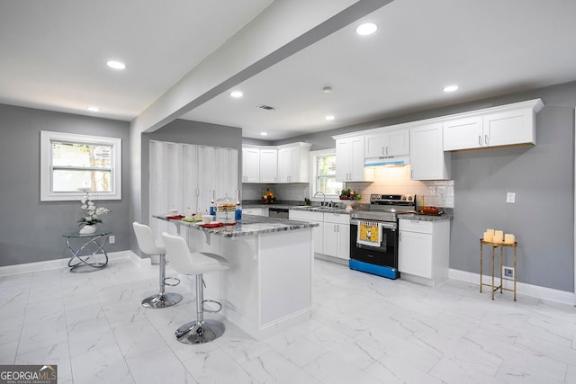 kitchen featuring white cabinetry, stainless steel electric range oven, a breakfast bar area, and stone counters