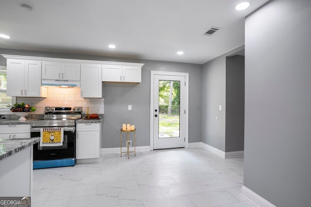 kitchen featuring stainless steel electric stove, light stone countertops, white cabinets, and decorative backsplash