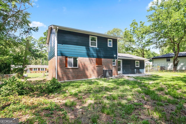 back of house with central air condition unit, a patio area, and a lawn