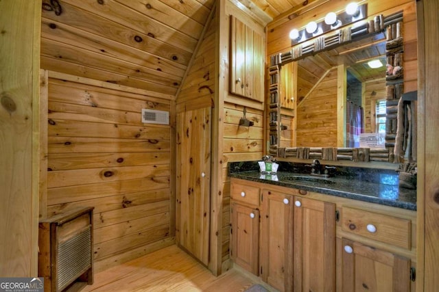 bathroom featuring wooden walls, lofted ceiling, hardwood / wood-style flooring, vanity, and wooden ceiling