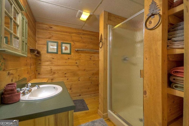 bathroom with hardwood / wood-style flooring, vanity, an enclosed shower, and wood walls