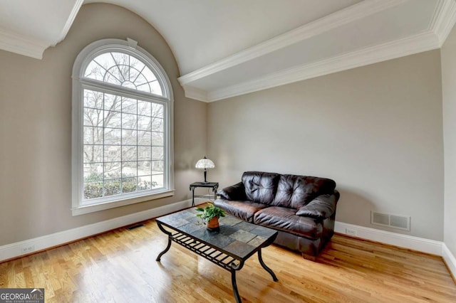 living room featuring vaulted ceiling, ornamental molding, and hardwood / wood-style floors