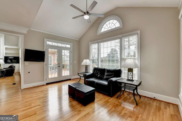 living room with french doors, high vaulted ceiling, light hardwood / wood-style flooring, ornamental molding, and ceiling fan