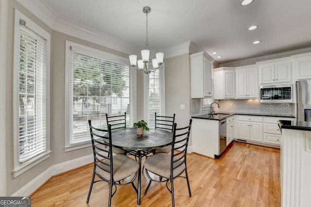 dining room featuring an inviting chandelier, sink, crown molding, and light wood-type flooring