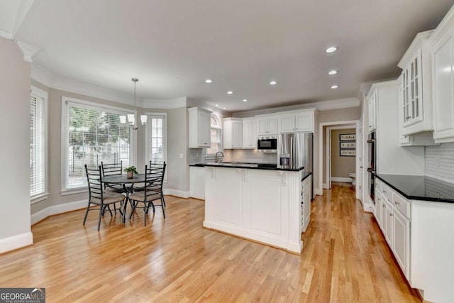 kitchen featuring white cabinetry, stainless steel appliances, crown molding, and hanging light fixtures